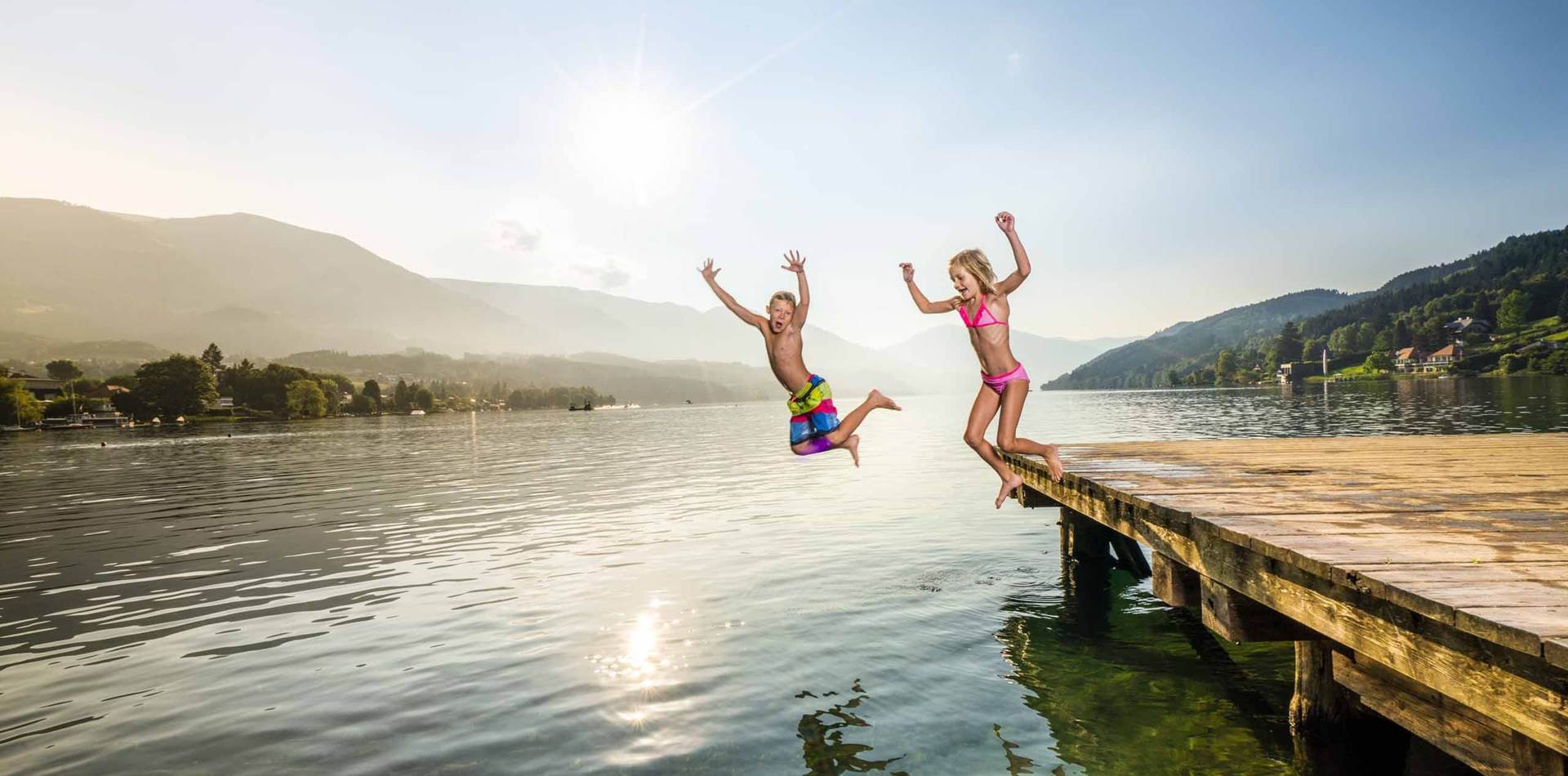 Zwei Kinder springen vom Steg in den Millstätter See